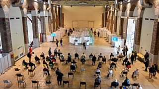 People wait at a vaccination center in Milan, Italy, Friday, April 16, 2021.