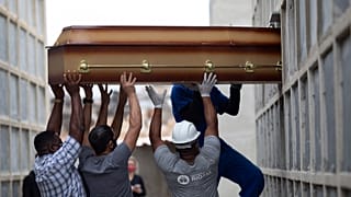 FILE - In this April 13, 2021, file photo, the remains of a woman who died from complications related to COVID-19 are placed into a niche by cemetery workers.