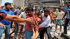 Rescuers assist an injured woman after an eight-story building housing several garment factories collapsed in Savar, near Dhaka, Bangladesh, Wednesday, April 24, 2013