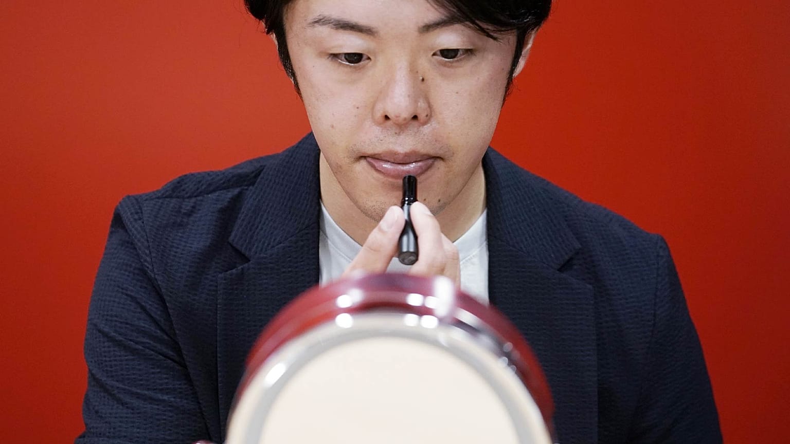 Naruhiko Ito, assistant brand manager of Shiseido Group, demonstrates their latest lip balm for men