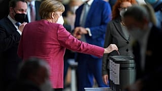 Angela Merkel dépose un bulletin dans une urne, lors d'une session parlementaire, Berlin, le 21 avril 2021