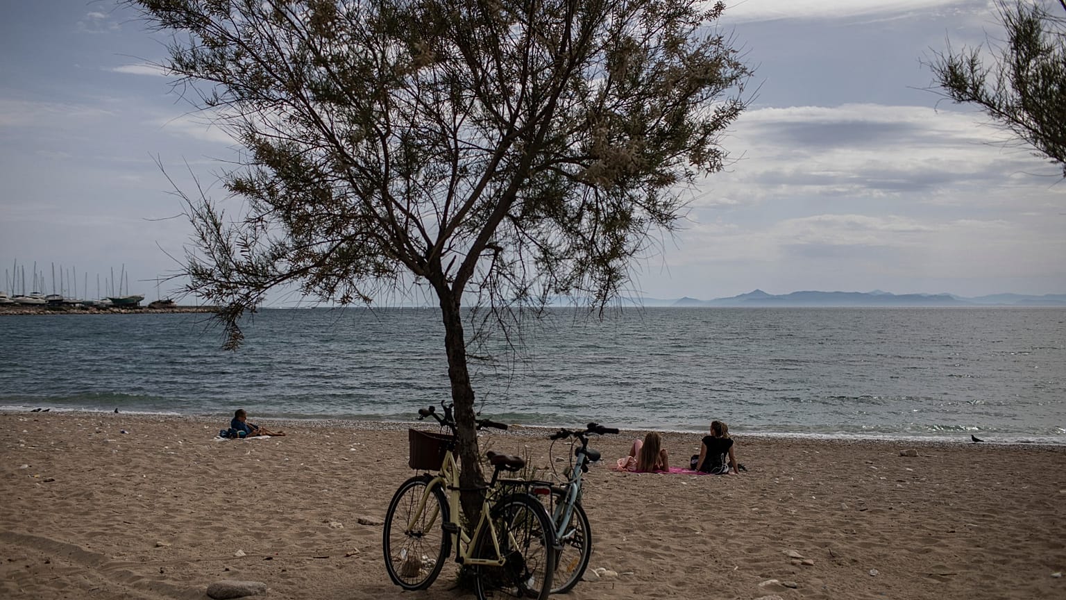 People sit a beach in Alimos, a seaside suburb of Athens, on Friday April 23, 2021. 