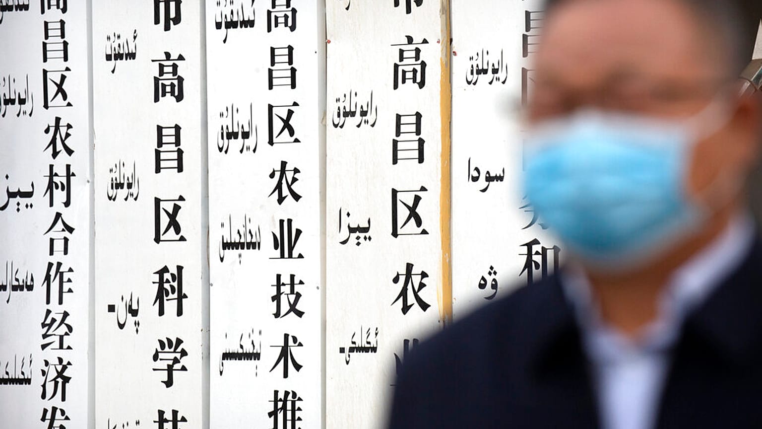 A government official stands near a sign board outside a location that was identified in early 2020 as a re-education facility by an Australian think tank.