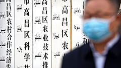 A government official stands near a sign board outside a location that was identified in early 2020 as a re-education facility by an Australian think tank.
