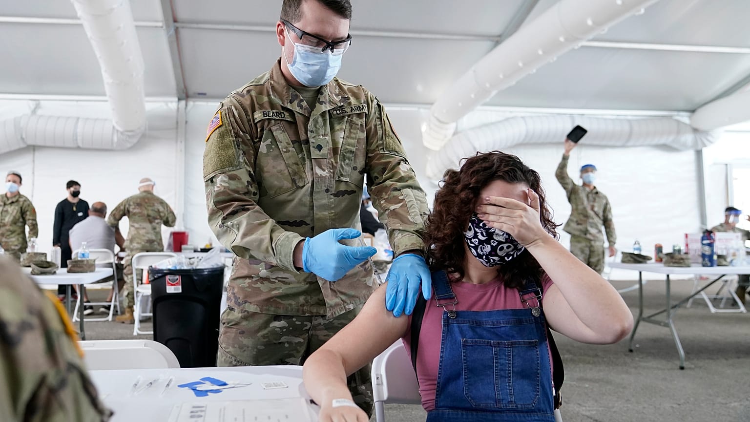 Une jeune femme se cache les yeux au moment de recevoir une dose de vaccin anticovid Pfizer, le 5 avril 2021, à Miami, Floride, États-Unis