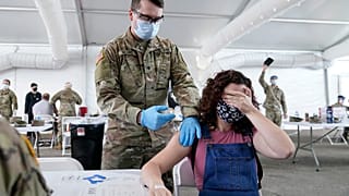 Une jeune femme se cache les yeux au moment de recevoir une dose de vaccin anticovid Pfizer, le 5 avril 2021, à Miami, Floride, États-Unis
