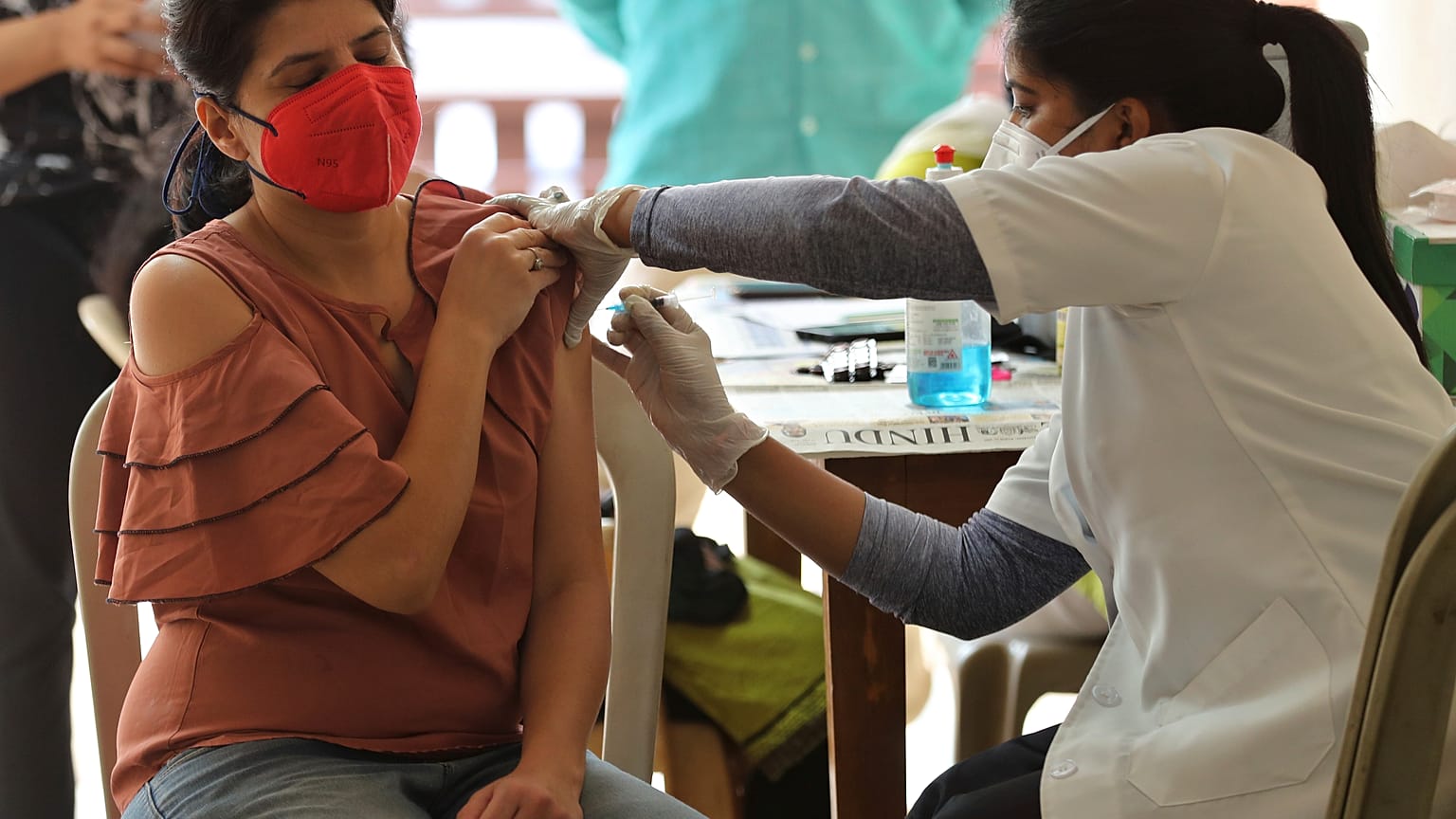 A woman reacts as she receives the AstraZeneca vaccine for COVID-19 at an apartment building in Bengaluru, India, Saturday, April 24, 2021.