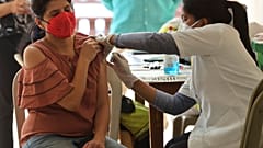 A woman reacts as she receives the AstraZeneca vaccine for COVID-19 at an apartment building in Bengaluru, India, Saturday, April 24, 2021.