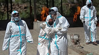 A relative of a person who died of COVID-19 is consoled by another during cremation in Jammu, India, Sunday, April 25, 2021. 