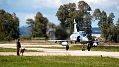 A Greek crew of a Mirage 2000-5 taxis as a soldier with a dog guards at Andravida air base, about 279 kilometres (174 miles) southwest of Athens, Tuesday, April 20, 2021. 