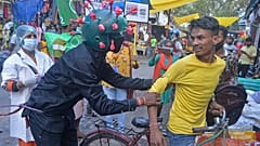 A man from a Non-governmental organization (NGO) wearing an outfit resembling the Covid-19 coronavirus moves around a marketplace urging people to follow the safety protocols 