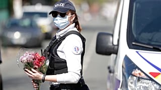 Une policière tient des fleurs que des habitants de Rambouillet lui ont donné, pour qu'il soit déposé sur les lieux de l'assassinat de Stéphanie Monfermé