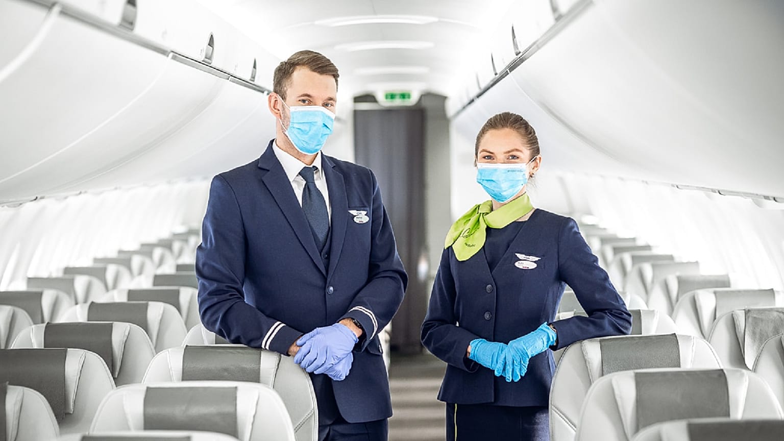 Members of the cabin crew welcome passengers on board an airBaltic flight during COVID-19.
