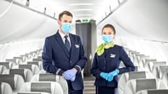Members of the cabin crew welcome passengers on board an airBaltic flight during COVID-19.