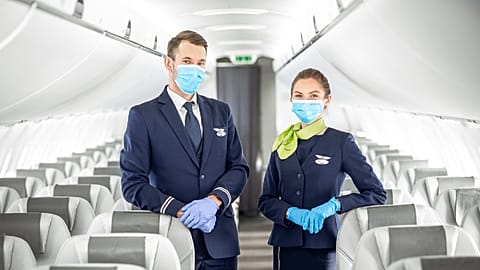 Members of the cabin crew welcome passengers on board an airBaltic flight during COVID-19.