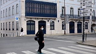 People wearing face masks walk across a street in Lisbon, Wednesday, Feb. 17, 2021. 