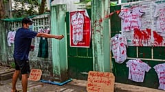 An anti-coup protester splashes red paint on student uniforms after they hanged them outside a school during a demonstration against the re-opening of the school by the junta 