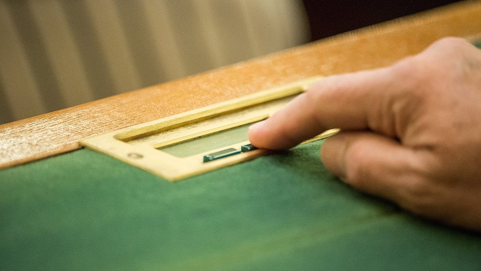 Szavazógombot nyom egy képviselő a magyar Parlamentben 2021. április 27.-én
