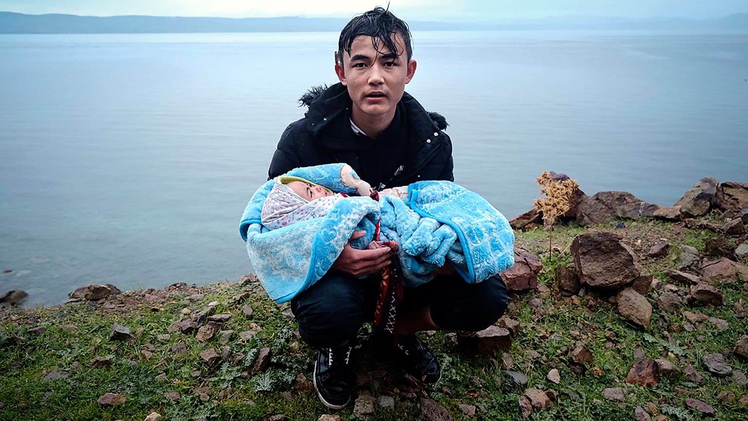 Ege Denizi'ni sandalla geçtikten sonra Yunanistan'ın Midilli adasına bağlı Skala Sikaminias köyüne yürürken kucağındaki bebekle yol kenarında dinlenen bir göçmen