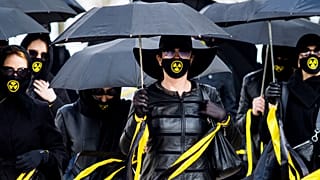 Women wearing black clothing and face masks with radioactivity sign march under umbrellas in Minsk. April 26, 2021