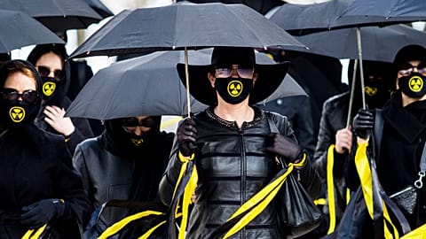Women wearing black clothing and face masks with radioactivity sign march under umbrellas in Minsk. April 26, 2021