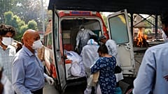 Profissionais de saúde transferem corpos de uma ambulância para um crematório em Nova Deli