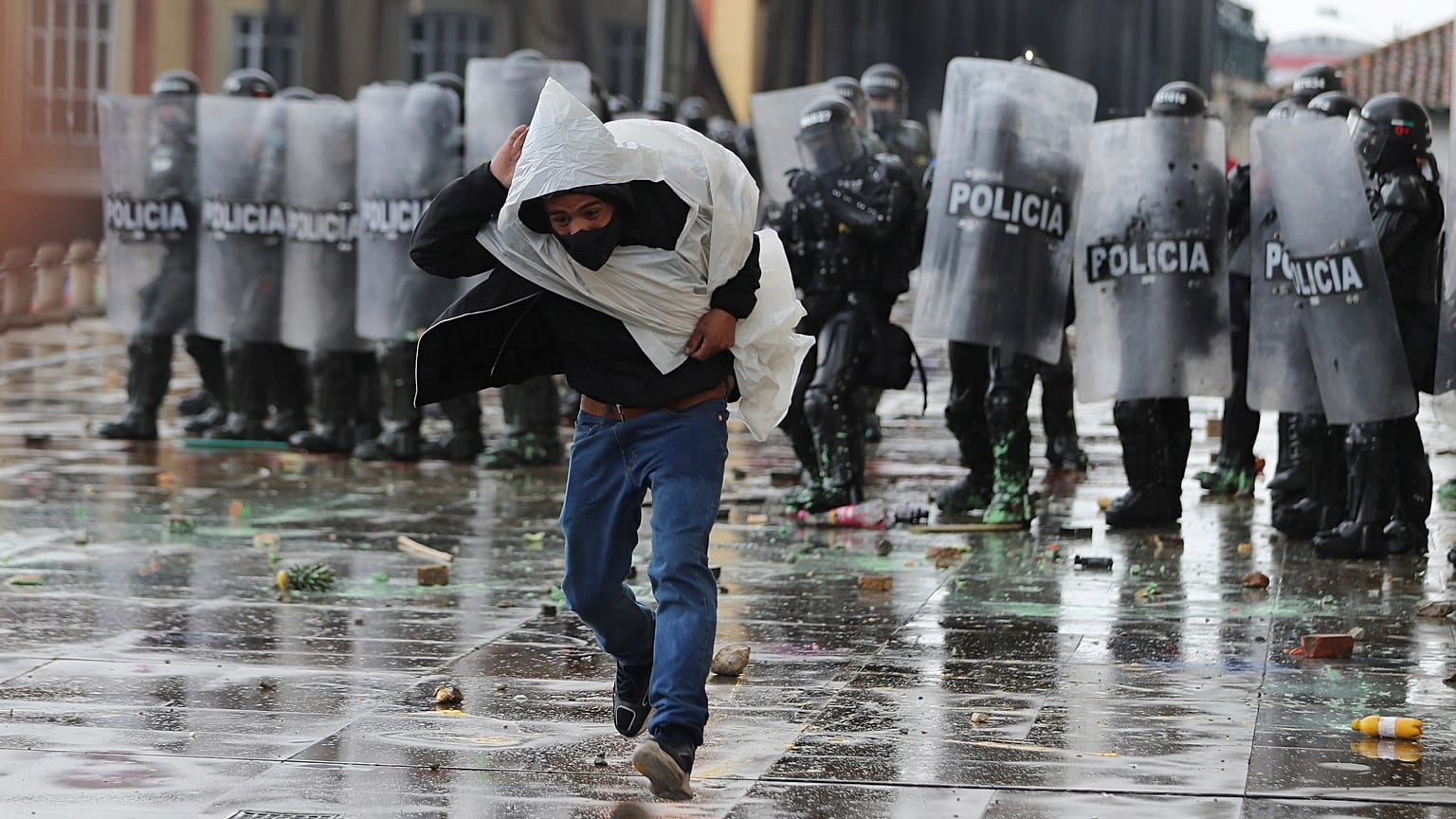 Un hombre huye de la policía tras lanzarle piedras durante una protesta en Colombia
