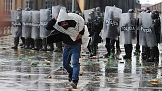 Un hombre huye de la policía tras lanzarle piedras durante una protesta en Colombia