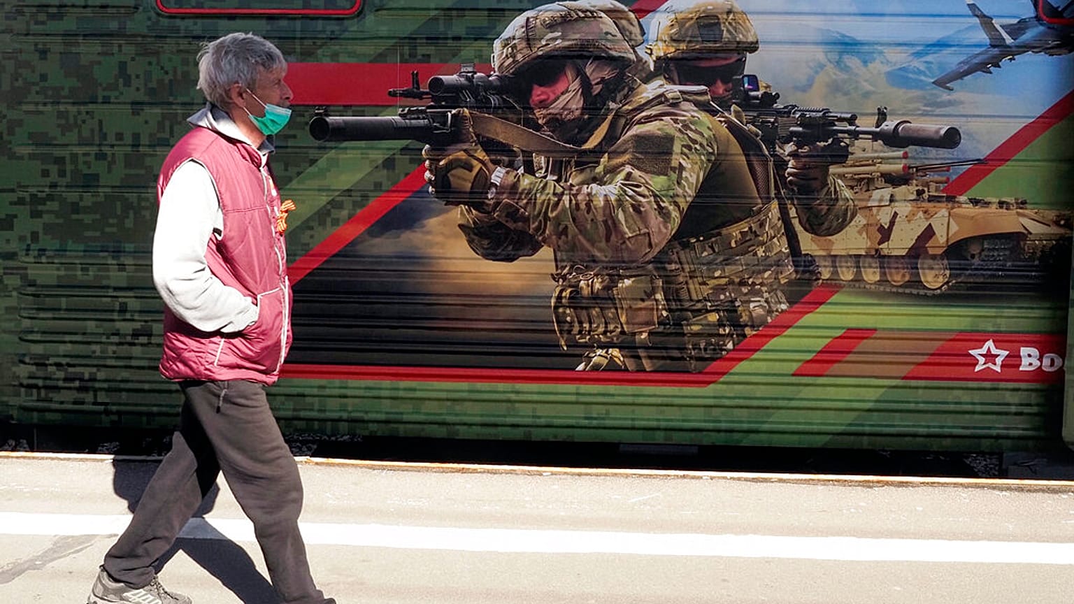 Мужчина в маске проходит мимо графити. 