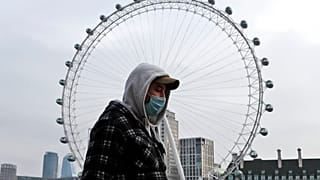FILE: a man wearing a face covering walks past the London Eye in London, Jan. 8, 2021.