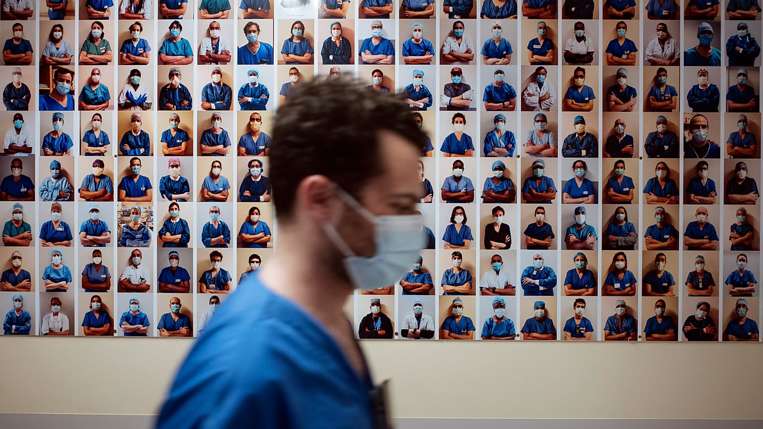 A member of staff passes in front of a collection of portraits of medical staff at Bichat Hospital, AP-HP, in Paris, Thursday, April 22, 2021.