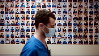 A member of staff passes in front of a collection of portraits of medical staff at Bichat Hospital, AP-HP, in Paris, Thursday, April 22, 2021.
