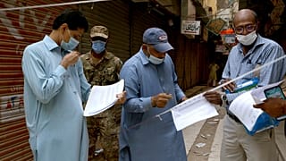 Officials gather to seal a market on the violation of new restrictions announced by government to control the spread of the coronavirus, in Karachi, Pakistan, Saturday.