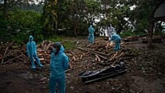 Health workers wearing personnel protection equipment wait for the cremation of a COVID-19 victim in Gauhati, India, Sept. 10, 2020.