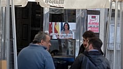People sit outside a bar with a poster of the president of the Madrid autonomous government, Isabel Diaz Ayuso, on March 22, 2021.