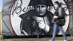 A woman walks past a picture of Napoleon Bonaparte in Corsica ahead of the bicentennial of his death.