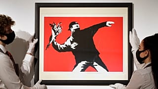 Gallery technicians display a Banksy artwork called "Love is in the Air" read for auction.