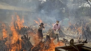 In this April 29, 2021, file photo, relatives react to heat emitting from the multiple funeral pyres of COVID-19 victims at a crematorium in the outskirts of New Delhi, India.