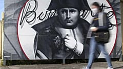 Eine Frau geht an einem Bild von Napoleon Bonaparte in Korsika vorbei