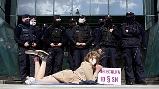 Policemen guard Poland's Supreme Court as a protester lies on the pavement in Warsaw, Poland, on Thursday, April 22, 2021.