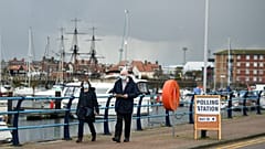 A couple walks past a sign for a Polling Station beside the marina in Hartlepool, north-east England on May 6, 2021