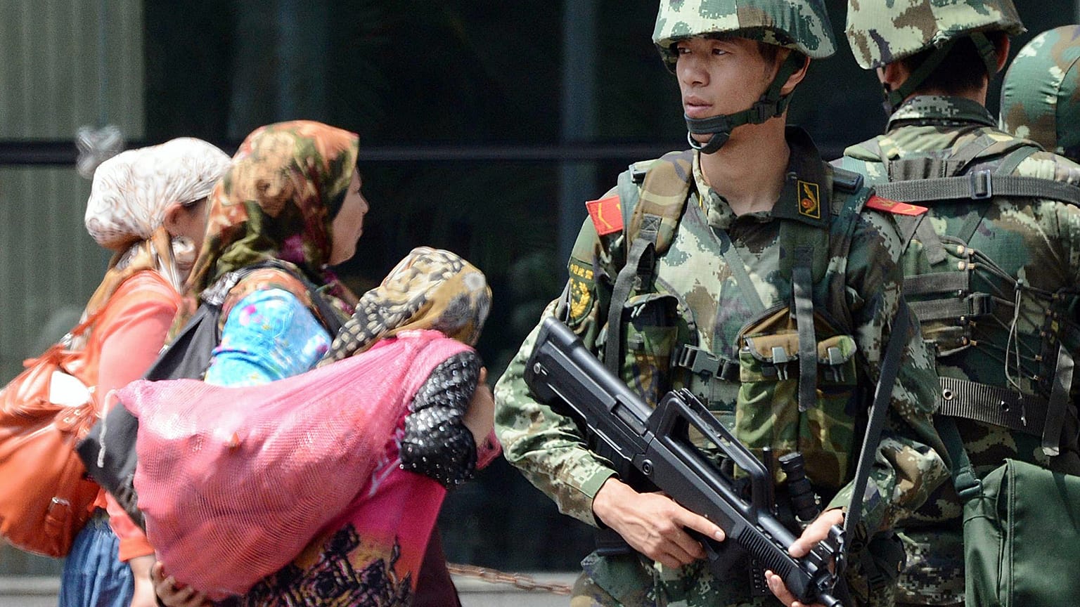 Doğu Türkistan'ın başkenti Urumçi'de Çinli paramiliter güçler ve buradan geçen Uygur kadınlar (arşiv)