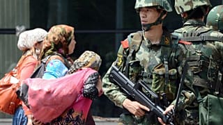 Doğu Türkistan'ın başkenti Urumçi'de Çinli paramiliter güçler ve buradan geçen Uygur kadınlar (arşiv)