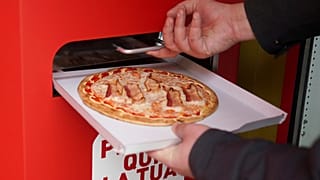 Elkészült pizzát vesz ki egy férfi az automatából