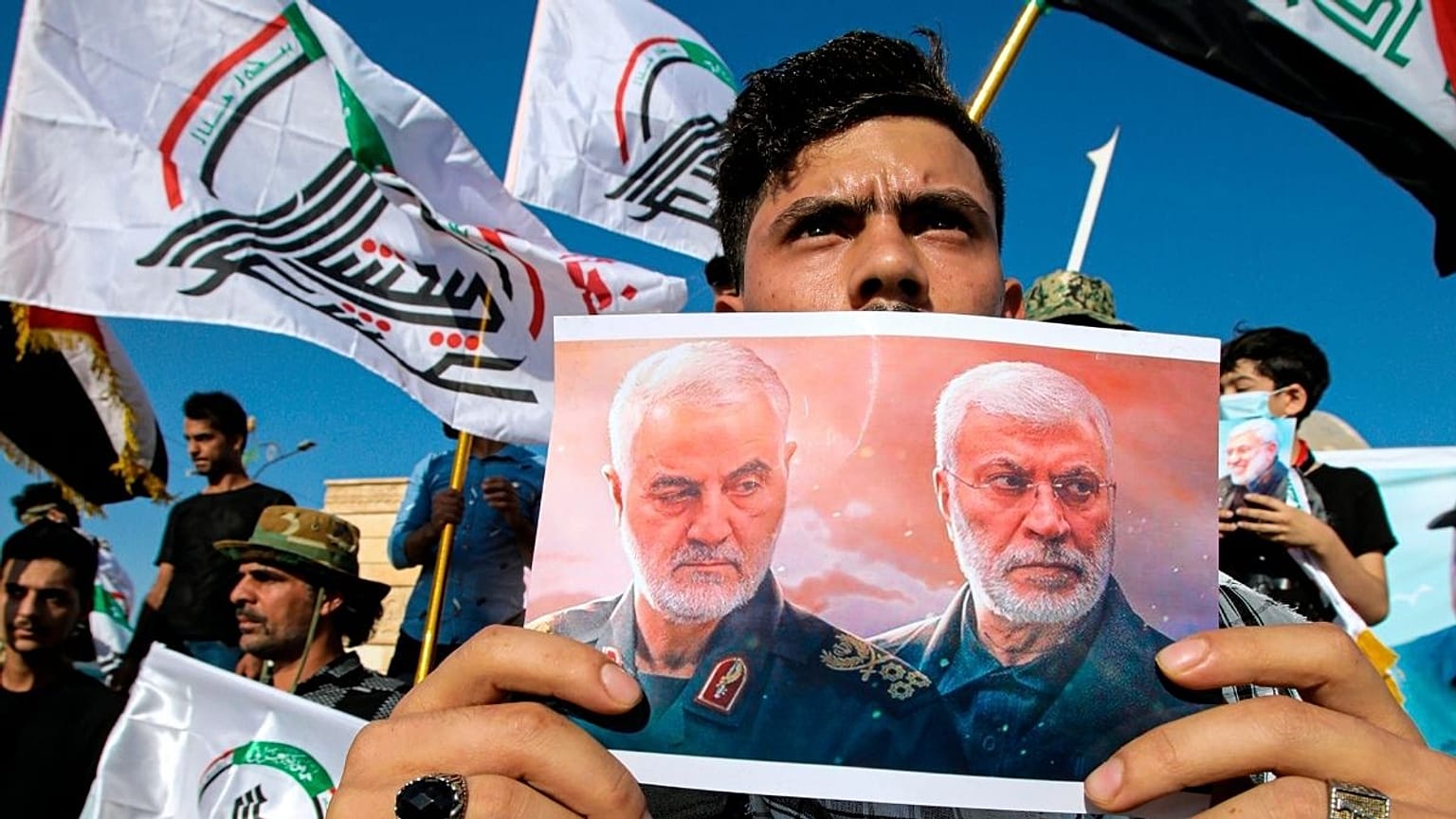 تصویر قاسم سلیمانی و ابومهدی مهندس در دست یکی از طرفداران شبه‌نظامیان شیعه در عراق