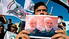 تصویر قاسم سلیمانی و ابومهدی مهندس در دست یکی از طرفداران شبه‌نظامیان شیعه در عراق