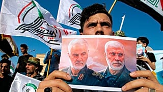 تصویر قاسم سلیمانی و ابومهدی مهندس در دست یکی از طرفداران شبه‌نظامیان شیعه در عراق