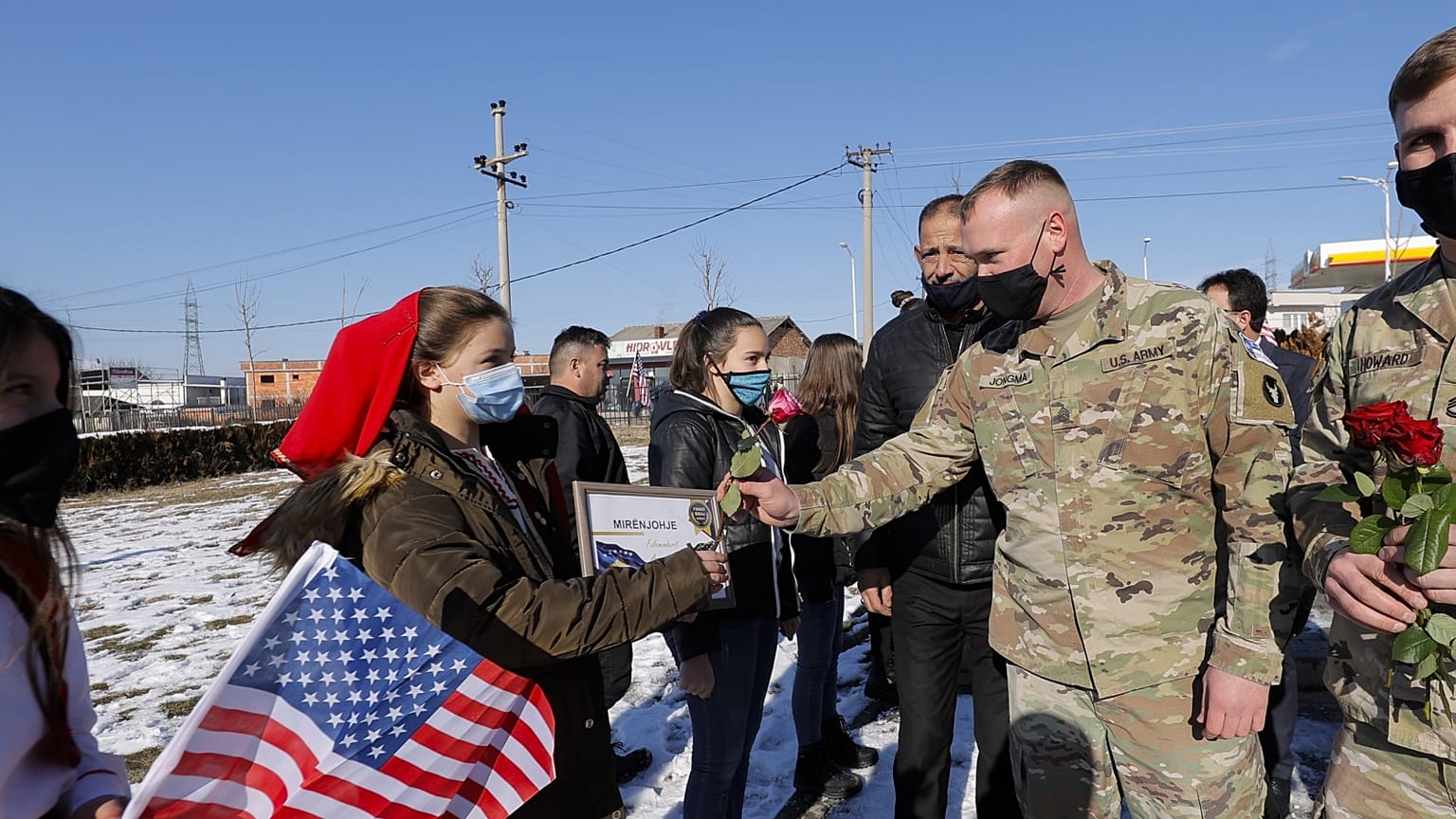 Koszovói albán nők virágot nyújtanak át amerikai békefenntartóknak, januárban