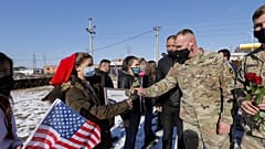 Koszovói albán nők virágot nyújtanak át amerikai békefenntartóknak, januárban