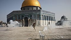 فلسطيني يهرب من الغاز المسيل للدموع خلال مواجهات مع قوات الأمن الإسرائيلية أمام مسجد قبة الصخرة في الحرم الأقصى